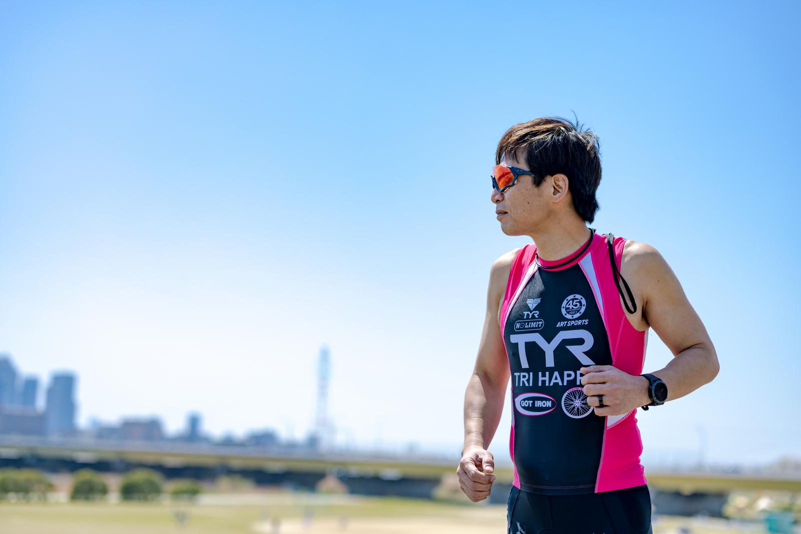 A male triathlete wearing sunglasses jogging on a river embankment (kasenshiki)