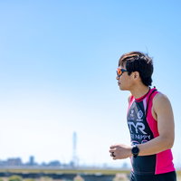 ランニングするトライアスリートの男性、ピンクと紺のウェア姿で力強く走るの写真
