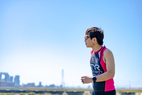 ランニングするトライアスリートの男性、ピンクと紺のウェア姿で力強く走る