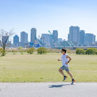 晴れた日に都市公園でランのトレーニングをするトライアスリートの写真