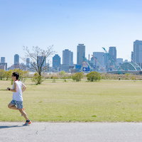 青空の河川敷をランニング中の男性、トレーニングに励む姿の写真