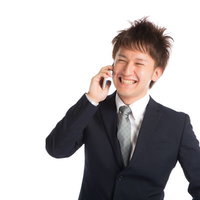 商談が決まり上司に電話で喜びを伝える若手商社マンの写真