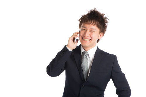 商談が決まり上司に電話で喜びを伝える若手商社マン