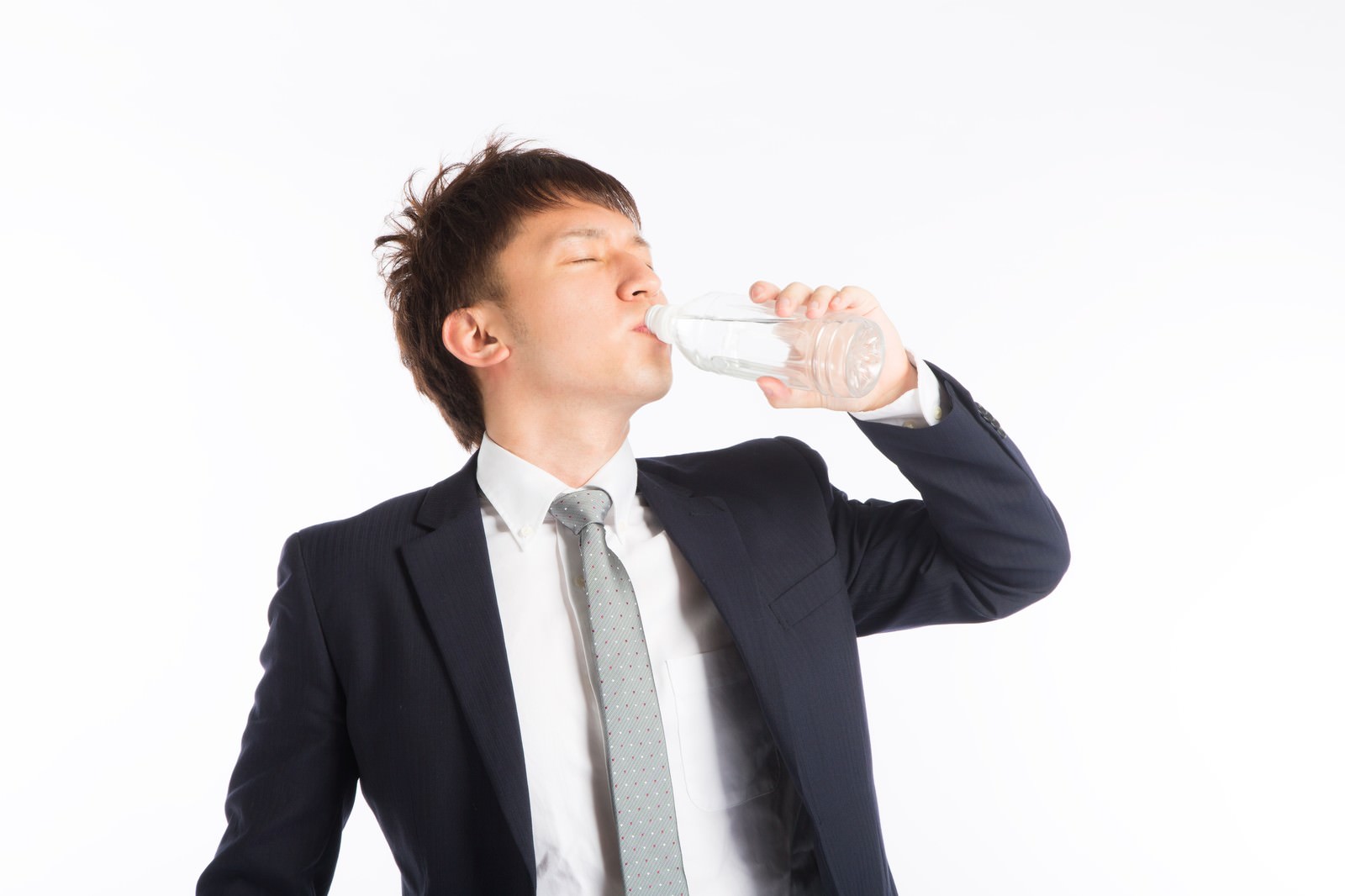 スーツ姿の男性がペットボトルの水を飲んでいる［モデル：鈴木秀］