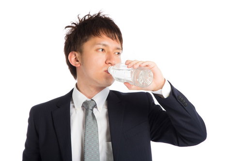 水を飲んで喉を潤すビジネスマン、スーツ姿で水分補給