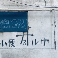 コンクリート壁に書かれた「小便スルナ」の警告文字の写真