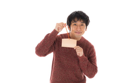 絵馬を手に取る祈願男子の正月参詣と初詣の願い事