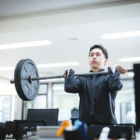 デスクの反対側で経営者がバーベルを持ち上げはじめたの写真