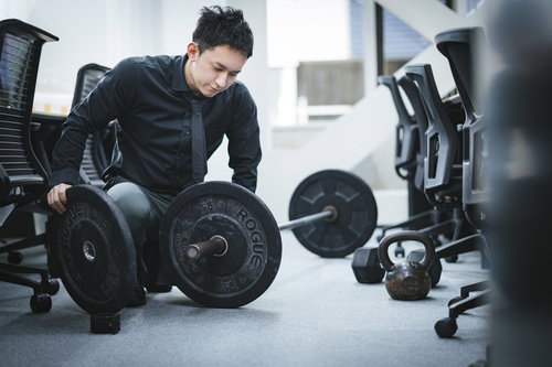 オフィスのジムでバーベルを準備する経営者の男性