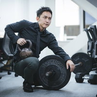 オフィスでケトルベルとバーベルのトレーニング器具を比較検討する経営者の写真