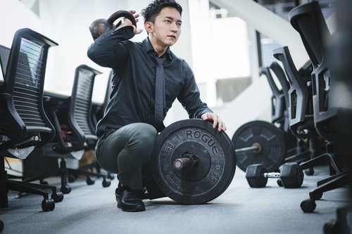 鋼鉄製のケトルベルを持つ男性経営者がオフィスでトレーニング