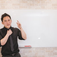 ホワイトボードの前で熱心に企画の趣旨を伝える男性の写真