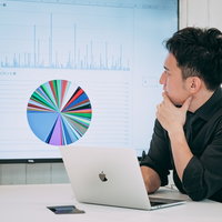 ディスプレイに表示された円グラフを見て経営状況を確認するCEOの男性の写真