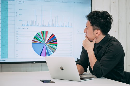 ディスプレイに表示された円グラフを見て経営状況を確認するCEOの男性