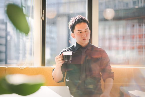 高層ビルが見えるカフェでコーヒーブレイクするマッスル経営者