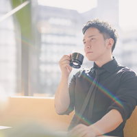コーヒータイム中でもイケてる経営者、高層ビルの窓辺での一息の写真