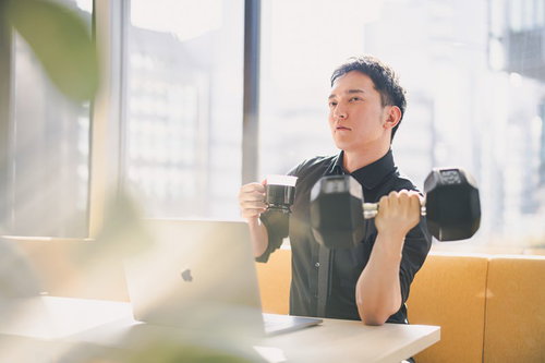 ダンベルで鍛えながら飲むプロテインで一息つく男性