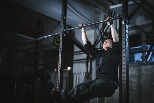 黒いシャツで鉄棒を使用して常に上を目指す経営者