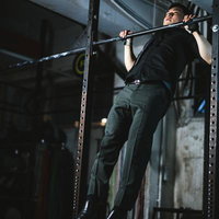 スーツ姿でジムの懸垂バーを使った上半身のトレーニングの写真