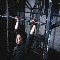 黒いシャツを着た男性が鉄棒で懸垂トレーニングの写真