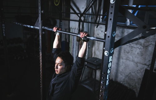 黒いシャツを着た男性が鉄棒で懸垂トレーニング