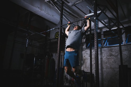 鉄棒でプルアップを繰り返す男性選手のトレーニング風景