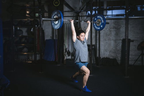 クリーンアンドジャークをスプリットスタンスで行う男性