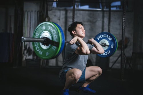 マッスル経営者がバーベルを担いでスクワットするトレーニング
