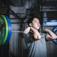 バーベルを担いで重量挙げするトレーニング中の男性の写真