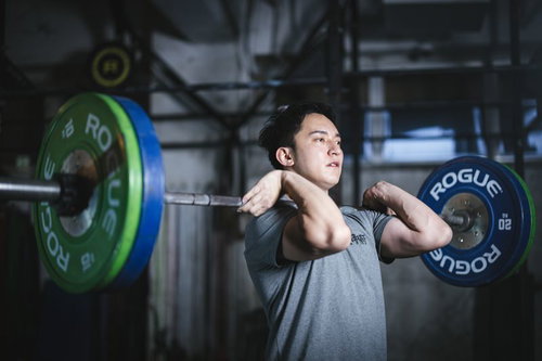 バーベルを担いで重量挙げするトレーニング中の男性