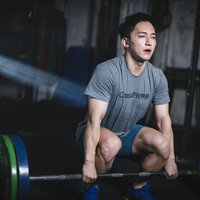 オーバーハンドグリップでバーベルを握るスクワット姿勢のマッスル男子の写真