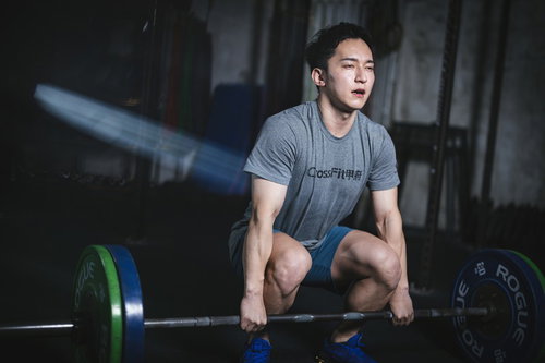 オーバーハンドグリップでバーベルを握るスクワット姿勢のマッスル男子