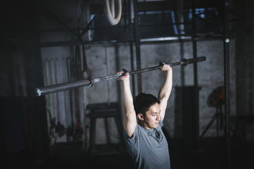 バーベルのバーのみでイメトレするウエイトリフティング男性