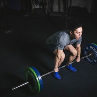 デッドリフトのスタートポジションでバーベルを握る男性アスリートの写真