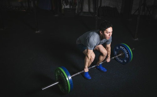 デッドリフトのスタートポジションでバーベルを握る男性アスリート
