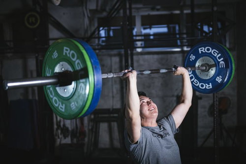 重いバーベルを両手で持ち上げるウエイトリフティングの男性