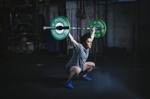 ジムでバーベルを頭上に挙げるウエィトトレーニングをする男性