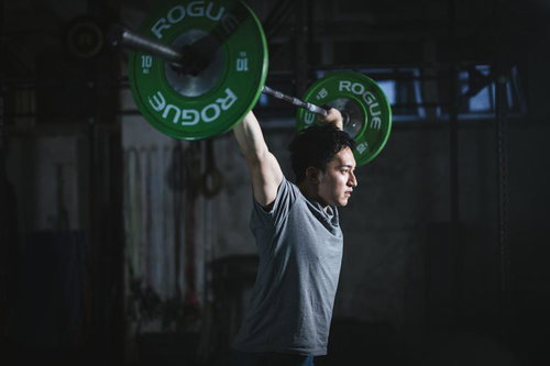 フィジカルモンスター経営者がバーベルを頭上に掲げるジムトレーニング