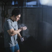 バーベルを上げる前に滑り止めの手を叩いて気合を入れる男性の写真