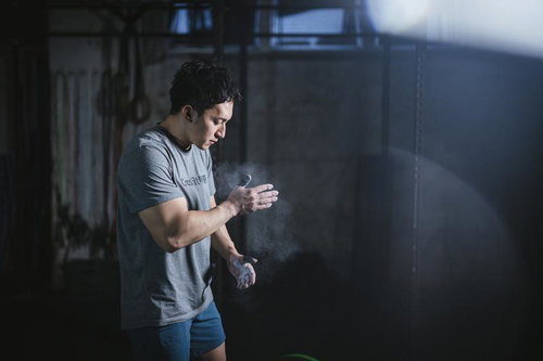 バーベルを上げる前に滑り止めの手を叩いて気合を入れる男性