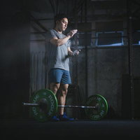 滑り止めの粉末を手に付けてバーベルを構える男性のウエィトトレーニングの写真