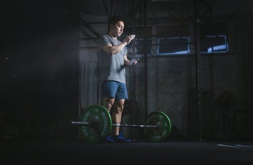 滑り止めの粉末を手に付けてバーベルを構える男性のウエィトトレーニング