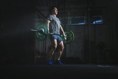 緑のバーベルを持ち上げるウエィトトレーニング中の男性