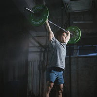 緑のプレートを上げてキープする男性のウエィトトレーニングの写真