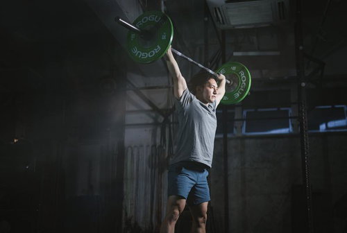 緑のプレートを上げてキープする男性のウエィトトレーニング