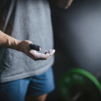 滑り止めパウダーをつけた手元でウエイトリフティングに挑むアスリートの写真