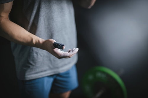 滑り止めパウダーをつけた手元でウエイトリフティングに挑むアスリート