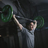 ジムでバーベルを頭上に掲げる筋トレ男性のウエイトトレーニングの写真