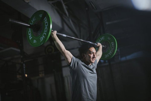 ジムでバーベルを頭上に掲げる筋トレ男性のウエイトトレーニング
