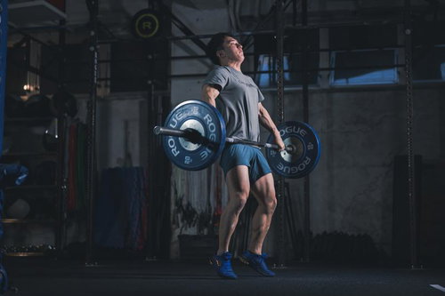 バーベルを担いで重量挙げを行う男性の筋トレ